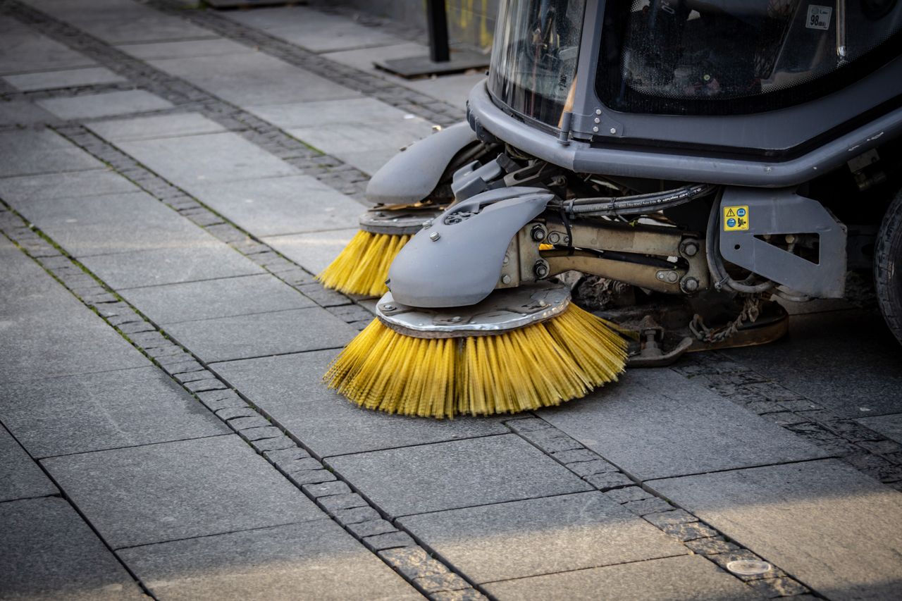 journey Close-up view of a road sweepers yellow brushes on a paved street.